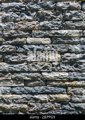 Vertikale Zusammensetzung grau rau Stein Wandstruktur. Teil eines alten, von Hand gefertigten, felsigen Hintergrunds mit Kopierraum. Wände aus Naturziegeln. Stockfoto