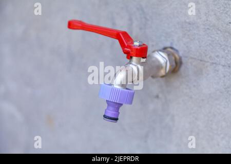 Metall-Wasserhahn auf der Straße für die Bewässerung von Bäumen und Blumen auf dem Grundstück platziert. Stockfoto