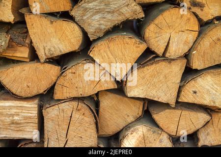 Durchbohrte Holzstämme aus Massivholz werden ordentlich gegen die Wand gelegt. Vorbereitung auf einen kalten Winter. Natürlicher Holzhintergrund Stockfoto