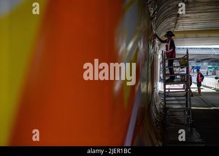 Magdeburg, Deutschland. 28.. Juni 2022. Die Künstlerin Claudia Walde sprüht ihr Graffito auf die Betonwand des Brückenlagers in einer Bahnüberführung am Hauptbahnhof. Es ist eines von zwei Graffiti von je 250 Quadratmetern des Künstlers, das die Wiederlagerung in Zukunft schmücken wird. Die Arbeiten sollten bis Ende der Woche abgeschlossen sein. Aus rund 300 Dosen wird dann Farbe auf den Beton gesprüht. Quelle: Klaus-Dietmar Gabbert/dpa/Alamy Live News Stockfoto