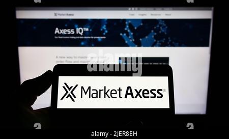 Person, die ein Smartphone mit dem Logo des US-Finanzunternehmens MarketAxess Holdings Inc. Auf dem Bildschirm vor der Website hält. Konzentrieren Sie sich auf die Telefonanzeige. Stockfoto