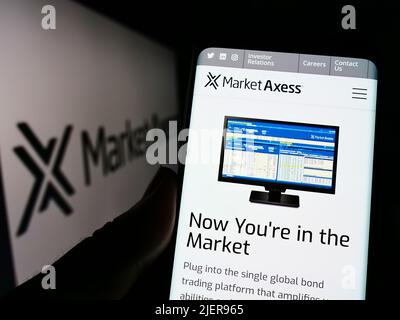 Person mit Smartphone und Website des US-Finanzunternehmens MarketAxess Holdings Inc. Auf dem Bildschirm mit Logo. Konzentrieren Sie sich auf die Mitte des Telefondisplays. Stockfoto