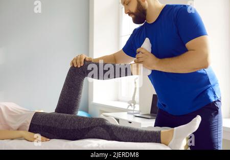 Der professionelle Masseur knetet in der Physiotherapie-Klinik das Bein der Patientin. Stockfoto