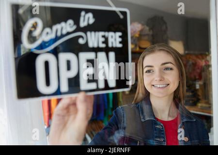 Lächelnde Inhaberin Eines Kleinbetriebes, Die Das Schild Im Schaufenster Öffnet Stockfoto