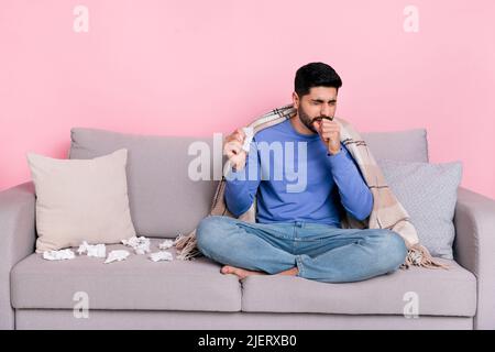 Foto von traurig krank arabischen Mann tragen Langarm Hemd sitzen Sofa Husten isoliert rosa Farbe Hintergrund Stockfoto