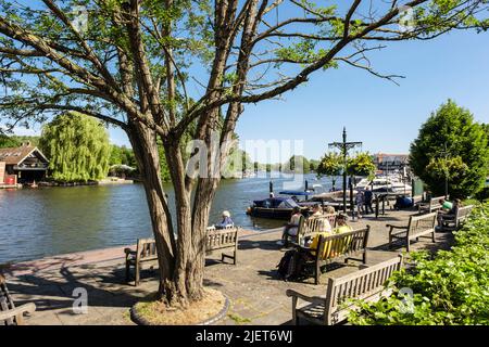 Im Sängerpark am Flussufer neben der Themse entspannen sich die Menschen auf den Sitzen bei Sonnenschein. Henley-on-Thames, Oxfordshire, England, Großbritannien Stockfoto