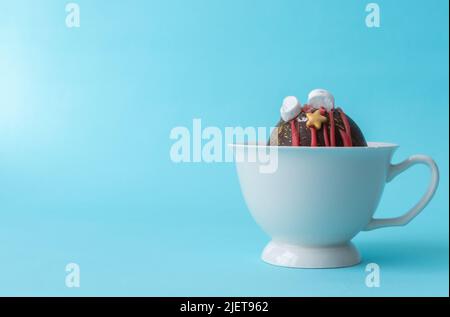 Schokoladen-Bombe mit handgefertigten Marshallows in einer weißen Tasse mit Milch auf blauem Hintergrund. Der Ort für Text ist auf der rechten Seite. Hochwertige Fotos Stockfoto