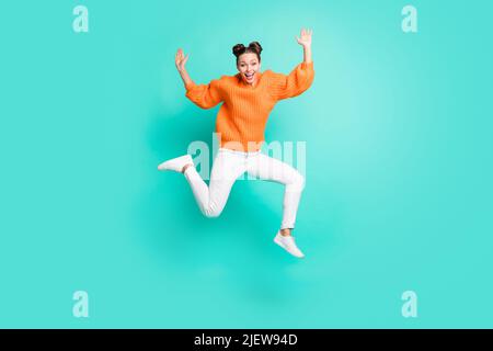 In voller Größe Foto von optimistisch schön Brunet Dame springen tragen Pullover Jeans isoliert auf blauem Hintergrund Stockfoto