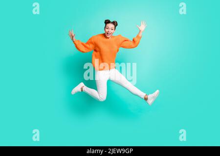 In voller Größe Foto von optimistisch schön Brunet Dame springen tragen Pullover Jeans isoliert auf blauem Hintergrund Stockfoto