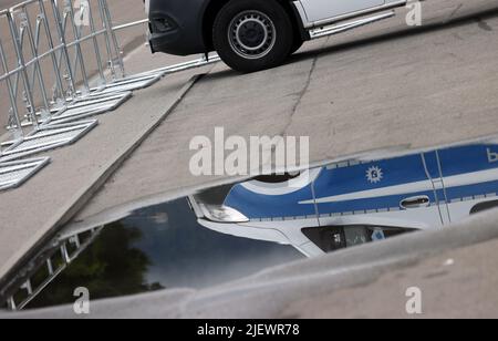 Garmisch Partenkirchen, Deutschland. 28.. Juni 2022. Ein Polizeiauto, das vor Barrieren steht, spiegelt sich in einer Pfütze von Regen wider. Deutschland war Gastgeber des Gipfels G7 auf Schloss Elmau. Quelle: Karl-Josef Hildenbrand/dpa/Alamy Live News Stockfoto