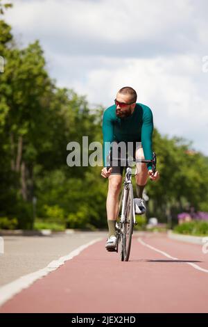 Porträt eines sportlichen Mannes in einem Radsport-Outfit, der mit einem Fahrrad auf der Bike Lane steht und für die Kamera posiert Stockfoto