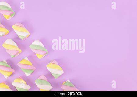 Pastellfarbene Süssigkeiten in der Ecke mit violettem Hintergrund und Platz zum Kopieren Stockfoto