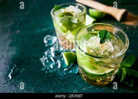 Von oben aus Gläser gefüllt mit erfrischenden Caipirinha-Getränken mit Eiswürfeln und Limette auf dunklen nassen Tisch gelegt Stockfoto