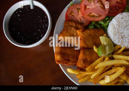 Nahaufnahme von typisch brasilianischem Combo-Teller, Reis, gebratenem Fisch, pommes Frites, Salat und Feijoada. Stockfoto