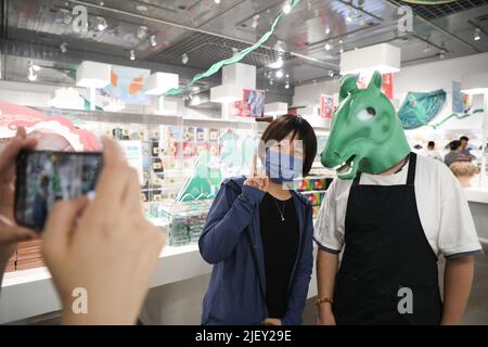 LANZHOU, 28. Juni 2022 (Xinhua) -- Ein Tourist (L) posiert für Fotos mit einem Mitarbeiter, der Kopfbedeckung mit einer alten Bronzestatue in einem Geschäft im Gansu Provincial Museum in Lanzhou, der Hauptstadt der nordwestlichen Provinz Gansu, trägt, 28. Juni 2022. Die Bronzestatue, die im Volksmund als „Bronze Galoppierendes Pferd auf einer fliegenden Schwalbe“ bekannt ist, wurde 1960s aus dem Leitai-Grab der östlichen Han-Dynastie (25-220 n. Chr.) in Wuwei ausgegraben und ist heute im Gansu Provinzmuseum erhalten. (Xinhua/Ma Xiping) Stockfoto