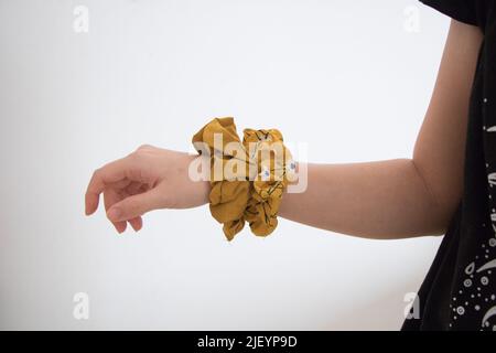 Mädchen mit zwei gelben Haarschrubben am Handgelenk Stockfoto