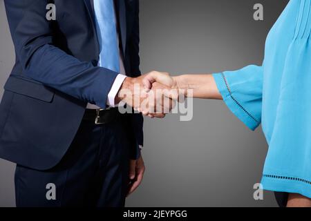 Nahaufnahme von zwei Geschäftsleuten, die sich die Hände schütteln, während sie auf einem isolierten grauen Hintergrund stehen. Speicherplatz kopieren. Stockfoto