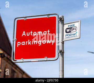 Ein roter automatischer Parkplatz und kostenlose WiFi-Schilder auf einem Pfosten gegen einen blauen Himmel im Stadtzentrum Stockfoto