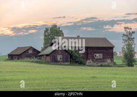 Die braunen Holzhäuser auf dem Land in Schweden unter dem Dämmerungshimmel Stockfoto