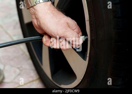 Nahaufnahme eines Mechanikers, der einen Autoreifen aufbläst Stockfoto