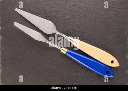 Zwei Metallmesser auf einem Schieferstein, Nahaufnahme, Draufsicht. Stockfoto