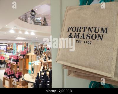 Stoffeinkauftaschen Fortnum und Mason im Innenraum der Food & Drinks Hall mit luxuriöser Präsentation von Getränken, Weinen und alkoholischen Getränken. Stockfoto