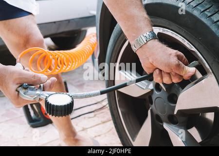 Nahaufnahme eines Mechanikers, der einen Autoreifen aufbläst Stockfoto
