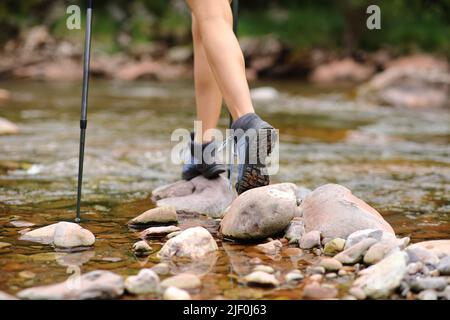 Nahaufnahme eines Trekkingbeines, der über den Fluss in den Bergen läuft Stockfoto