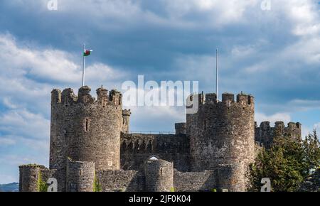 Über den massiven Steinmauern, die das historische Conwy Castle in Nordwales umgeben, sammeln sich Sturmwolken Stockfoto