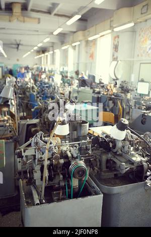 Inneneinrichtung der Fabrik mit manuellen Drehmaschinen, die mit Röhren und Lampen mit flexiblen Hälsen verbunden sind, Kopierfläche Stockfoto