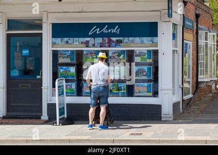 Mann mit einem Kinderwagen, der auf ein Fenster von Immobilienmaklern schaut, Stationen, tenterden, kent, großbritannien Stockfoto