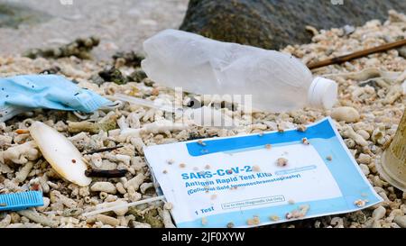 Medizinische Gesichtsmaske und Covid-Test am Strand verwendet. Übernutzung von chirurgischen Masken und Selbsttests während der Coronavirus-Pandemie. Stockfoto