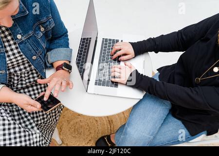 Blick von oben auf zwei Frauenhände, die am Computer und Telefon arbeiten Stockfoto