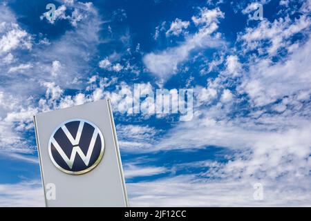 AUGSBURG, DEUTSCHLAND – 16. JUNI 2022: Werbeschild der Automobilmarke VW Volkswagen vor einem wolkenbewölkten Himmel Stockfoto