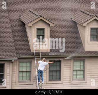 Maler auf der Leiter mit Druckwaschspray, um Holzarbeiten vor dem Lackieren Stadthaus zu reinigen Stockfoto