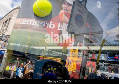 Im Fenster eines Busses spiegelt sich die britische Tennisspielerin Emma Raducanu am zweiten Wettkampftag während der Wimbledon Lawn Tennis Association Championships am 28.. Juni 2022 in London, England, auf einer riesigen Werbetafel im Stadtzentrum von Wimbledon wider. Stockfoto