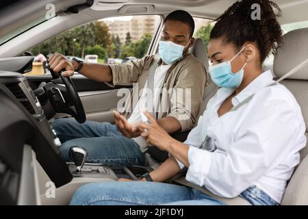 Afroamerikanisches Paar, Das Hände Mit Desinfektionsmittel-Spray Im Auto Desinfiziert Stockfoto