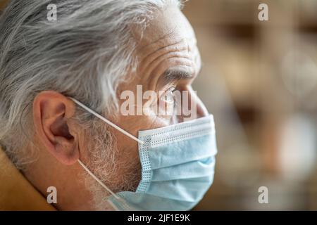 Nahaufnahme eines älteren Mannes, der eine schützende Gesichtsmaske trägt Stockfoto
