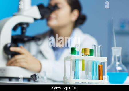 Nahaufnahme von Reagenzgläsern, die mit bunten medizinischen Proben gefüllt sind und im Rack auf dem Tisch des Laboranten platziert sind Stockfoto