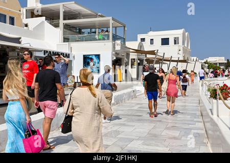 Oia, Santorini, Griechenland - 2022. Juni: Menschen, die in der Stadt Oia an Geschäften vorbeilaufen. Stockfoto
