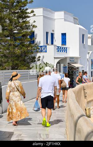 Oia, Santorini, Griechenland - 2022. Juni: Menschen, die in der Stadt Oia an Geschäften vorbeilaufen. Stockfoto