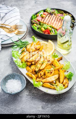 Kartoffelkeile, im Ofen gebraten mit frisch gemischtem Salat und gegrilltem Käse Stockfoto