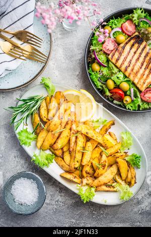 Kartoffelkeile, im Ofen gebraten mit frisch gemischtem Salat und gegrilltem Käse Stockfoto