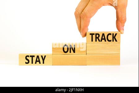 Symbol „auf Kurs bleiben“. Konzeptwörter bleiben auf Holzblöcken auf einem schönen weißen weißen Hintergrund auf Kurs. Geschäftsmann Hand. Geschäft, Motivation Stockfoto