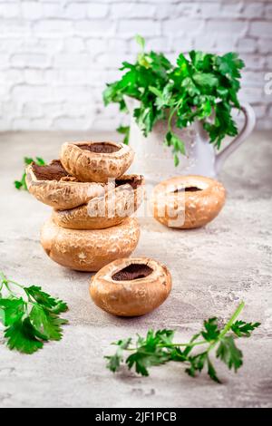 Rohe portobello-Pilze mit frischer Petersilie auf dem Küchentisch, zubereitet zum Kochen Stockfoto