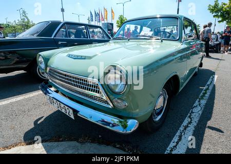 Ostrava, Tschechien - 06.05.2022: Frontalaufnahme eines hellgrünen Ford Consul-Oldtimerwagens mit niedrigem Winkel. Menschen bewundern Retro-Autos während Veteran Rallye-Veranstaltung Stockfoto