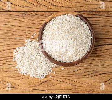 Roher Carnaroli-Risotto-Reis in einer Schüssel über einem Holztisch. Stockfoto