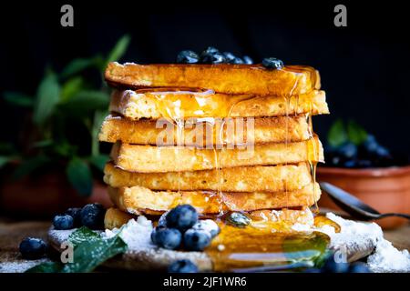 Waffeln mit frischen Heidelbeeren und Honig auf dem rustikalen Tisch. Frisch gebackene belgische Waffeln Stockfoto