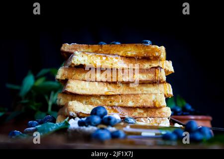 Waffeln mit frischen Heidelbeeren und Honig auf dem rustikalen Tisch. Frisch gebackene belgische Waffeln Stockfoto