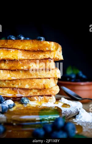 Waffeln mit frischen Heidelbeeren und Honig auf dem rustikalen Tisch. Frisch gebackene belgische Waffeln Stockfoto